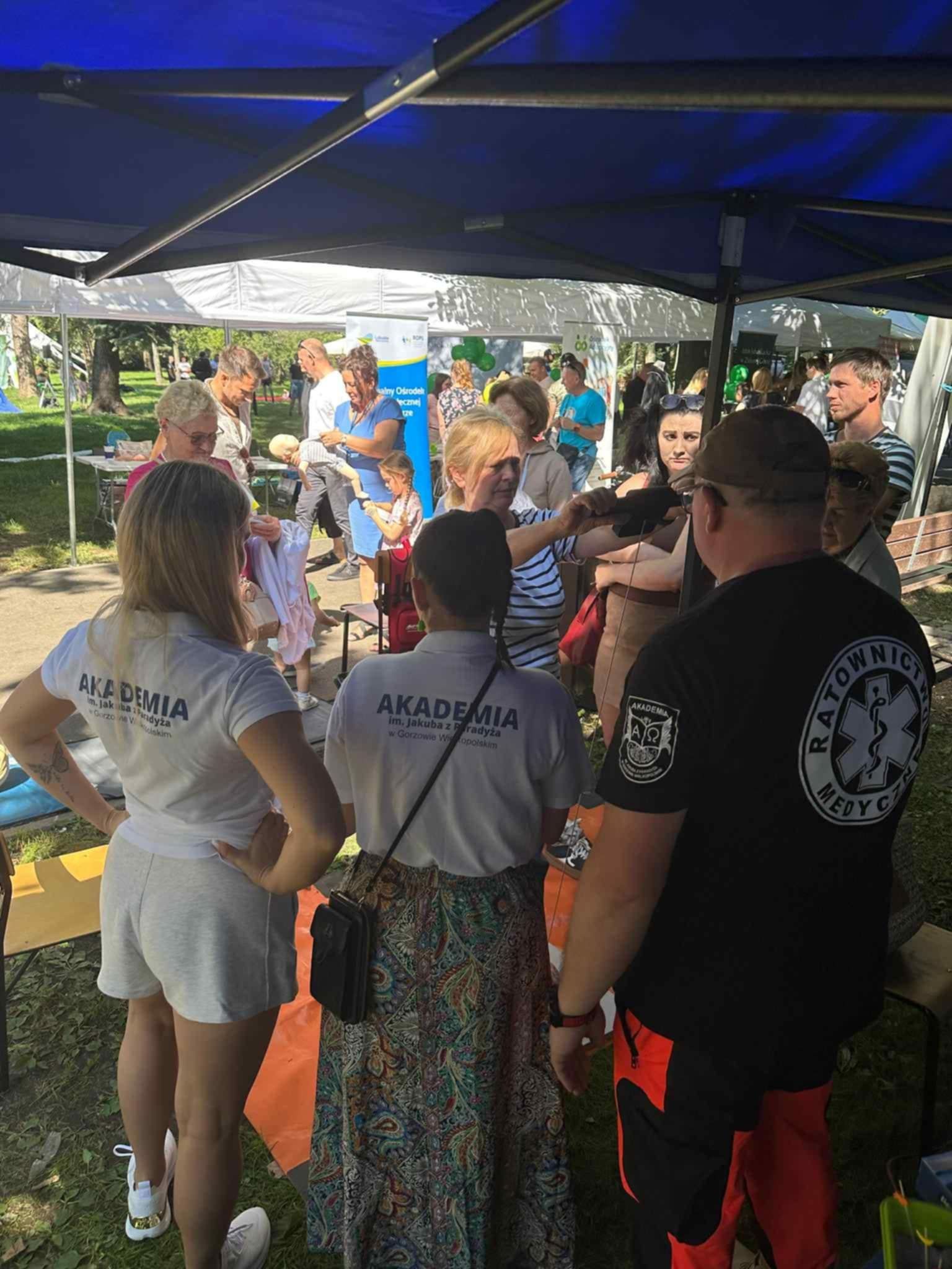 Uczestnicy Pikniku Zdrowia gromadzą się przy stanowisku Akademii im. Jakuba z Paradyża, gdzie prowadzone są pomiary i konsultacje zdrowotne.